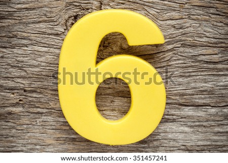 Yellow number six on the wooden background