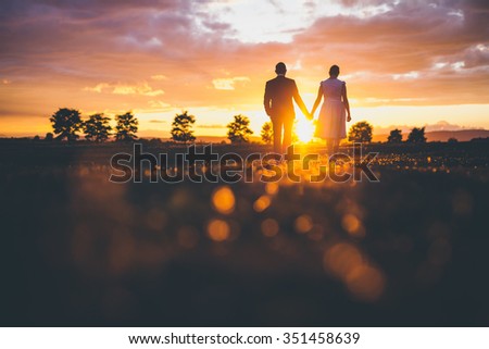 Couple holding hands in the sunset Royalty-Free Stock Photo #351458639