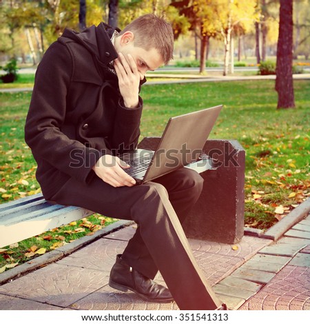 Toned Photo of Young Man with Laptop in the Autumn Park
