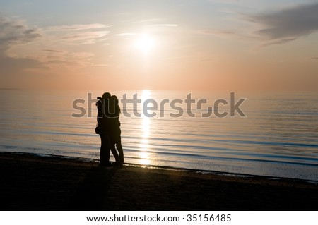 Man hugs a girl ashore sea on a background sunset