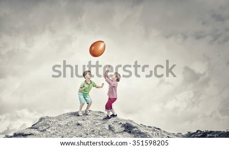 Little cute boys playing joyfully with colorful balloon