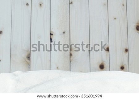 Winter background with snow on the background of a blurred wooden surface