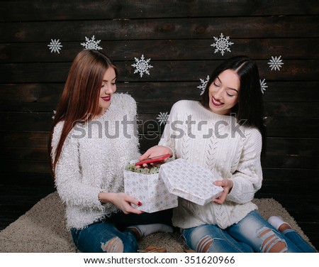 Two pretty young funny girls friends smiling and having fun, holding presents, smartfon