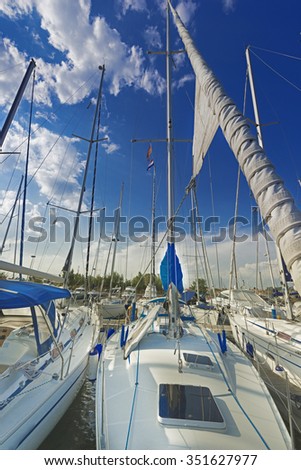 sailboat on the dock, blue sky, front sailboat, sails lowered