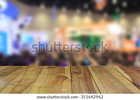wood table and  abstract blurred image of trade show for background