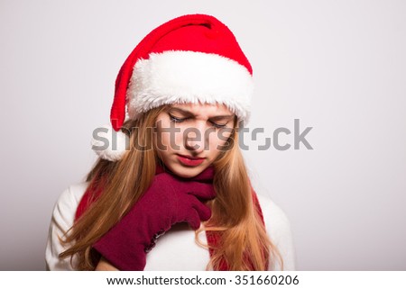 Christmas Santa hat isolated portrait of a girl. Sick, sore throat on a gray background