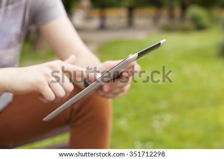 Young man read news and communicate on social networks with tablet computer in park