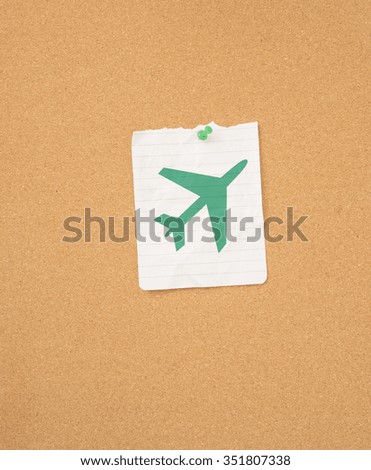 Airplane symbol as reminder on memo note pinned to message board. Concept of travel, flying and vacation.