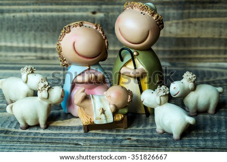 Closeup view of decorative celebrating Christmas and Jesus birth figurines of holy virgin Mary Joseph newborn child with few white sheeps standing on wooden background, horizontal picture