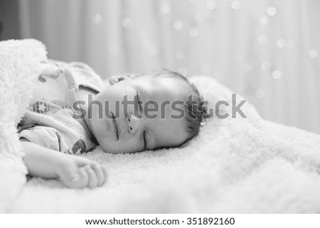 Black and white picture of newborn sleeping on back