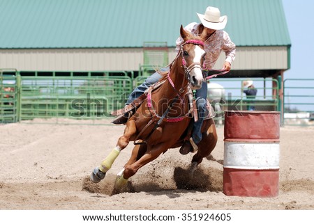 Cowgirl racing her horse between poles during a rodeo. Royalty-Free Stock Photo #351924605