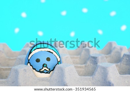 Christmas egg with faces drawn arranged in carton on snow background