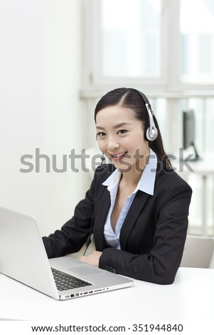Young woman using laptop and wearing headset