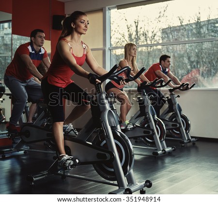 Young active people exercising in spinning class. Group of fit people doing sport in the gym. Royalty-Free Stock Photo #351948914