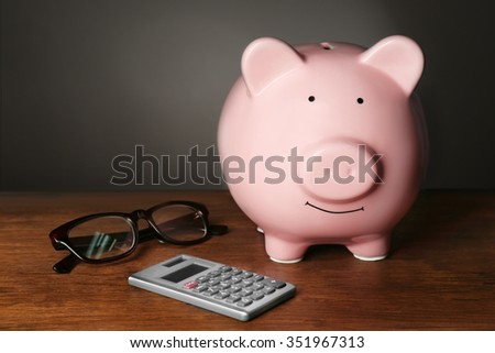 Piggy bank and calculator on table , gray background