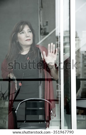 Beautiful mature woman looking out the window in a urban environment.
