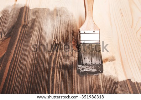 Grey color painting on wooden table or fence or wall, or flour, use for home decorated. House renovation. Half - painted surface. Smear of paint brush.