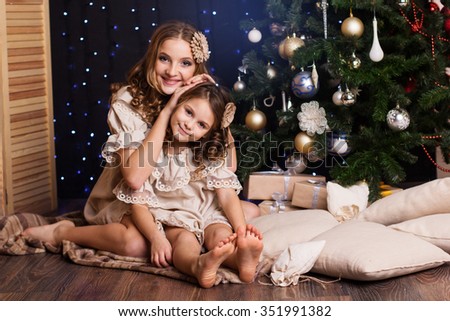 Pretty two girls are holding gifts near christmas tree