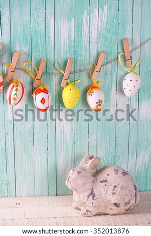 Colorful easter eggs on rope and decorative rabbit  on wooden background. Easter background.