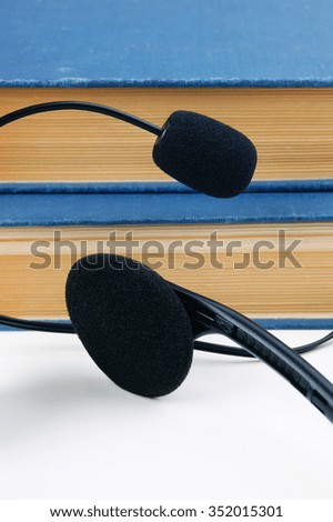 Headphones with a microphone and a stack of books on white background