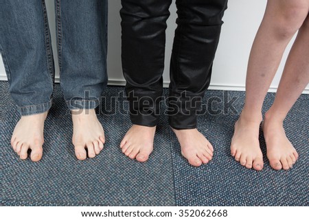 Feet of three people standing in a house 