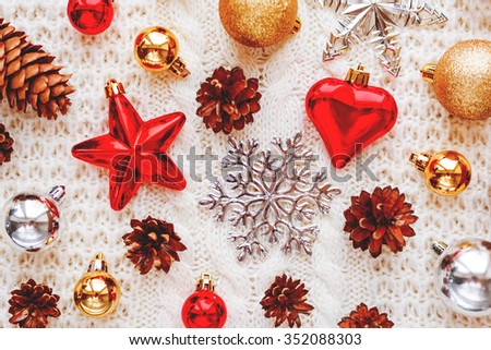 Christmas and New Year background with decorations - balls, stars, silver sparkling snowflakes, heart on knitted fabric with decorative pattern.