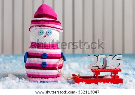 2016 year On red sled and handmade snowman on wooden background. Xmas card with empty space for text