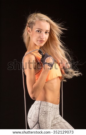 Sport, activity, fitness. Cute woman with skipping rope. Muscular girl black background.