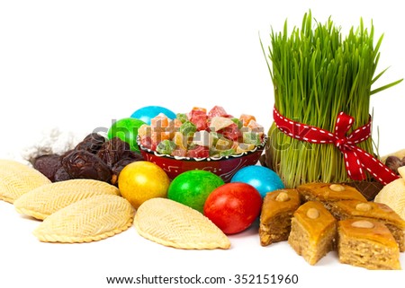 Novruz in Azerbaijan. Colored eggs for Easter and traditional sweets on white background. Selective focus.
