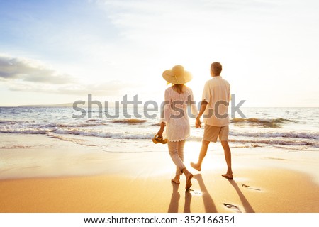 Happy Romantic Middle Aged Couple Enjoying Beautiful Sunset Walk on the Beach. Travel Vacation Retirement Lifestyle Concept Royalty-Free Stock Photo #352166354