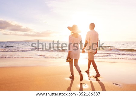 Happy Romantic Middle Aged Couple Enjoying Beautiful Sunset Walk on the Beach. Travel Vacation Retirement Lifestyle Concept Royalty-Free Stock Photo #352166387
