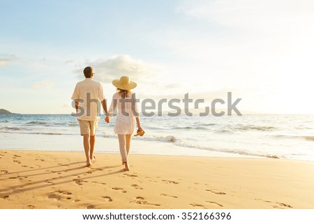 Happy Romantic Middle Aged Couple Enjoying Beautiful Sunset Walk on the Beach. Travel Vacation Retirement Lifestyle Concept Royalty-Free Stock Photo #352166396