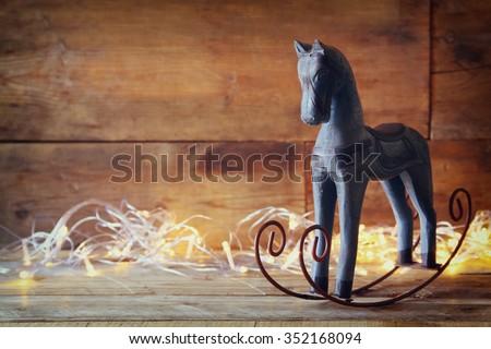 image of rocking horse and magic christmas lights on wooden table
