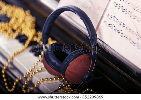 Brown headphones with golden decorations on piano keyboard, close up