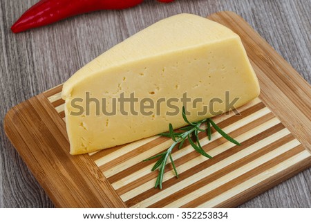 Yellow cheese triangle with rosemary herbs on the wood background