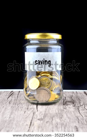 Glass jar with coins isolated on black background