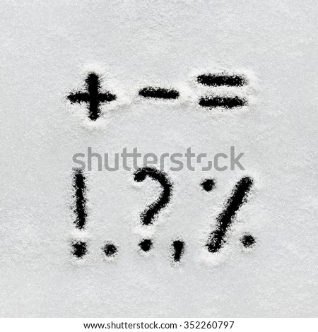 Winter alphabet, symbols and numbers hand written on snow. Black background isolated.