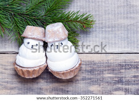 two little funny snowman and fir branch on a wooden surface.closeup.view from above