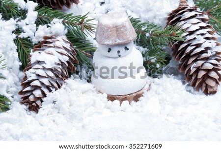 little snowman biscuit on spruce branches covered with artificial snow