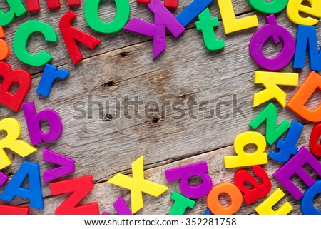 Top border of colorful toy magnetic letters over a wooden background