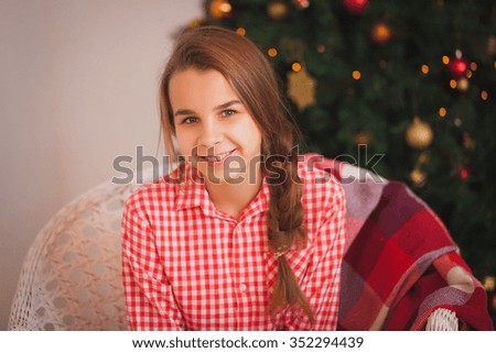 Teen girl in a red plaid shirt in Christmas decorations
