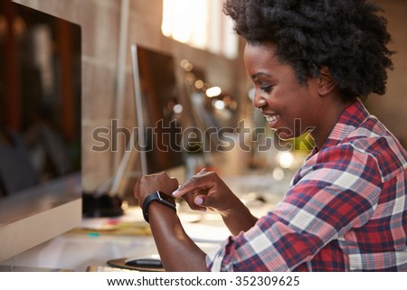 Businesswoman Looking At Smart Watch In Design Office Royalty-Free Stock Photo #352309625