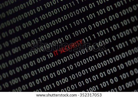 'IT security' text in the middle of the computer screen surrounded by numbers zero and one. Image is taken in a small angle.