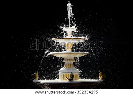 Splashing fountain in four levels on dark background Royalty-Free Stock Photo #352354295
