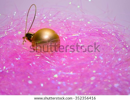 golden shiny christmas ball on a pale pink background 