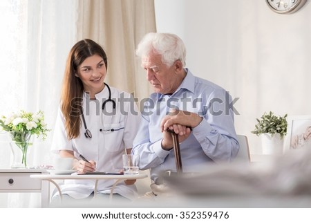 Elderly patient talking to young smiling community nurse Royalty-Free Stock Photo #352359476