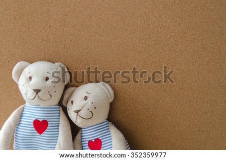 two teddy Bear with Heart on cork board background