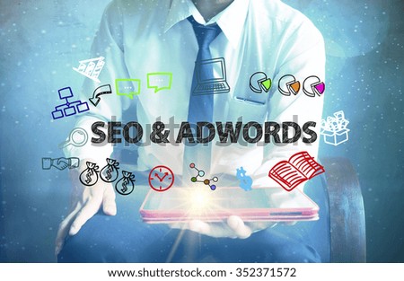 businessman holding a tablet computer with SEO & ADWORDS text ,business concept 