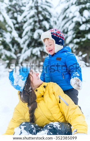 Outdoor portrait Mother and child playing in the winter park. The son hugged his mother