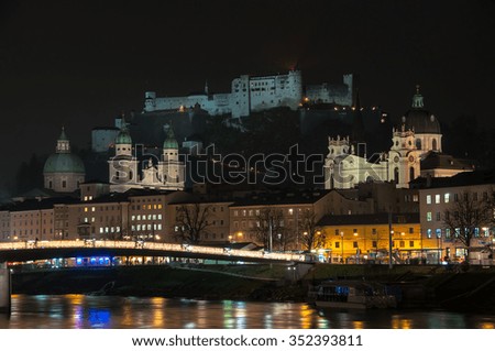 View of Salzburg, Austria at night. Illuminated Castle at the background, reflection in the river. Dark sky